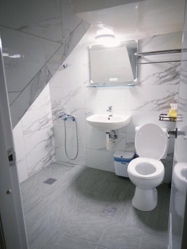 a white bathroom with a toilet and a sink at Ajuan Homestay in Hengchun South Gate