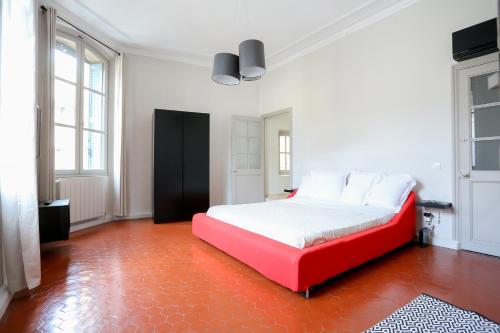 a bedroom with a red bed in a white room at L'Oustau D'Alberta in Aix-en-Provence