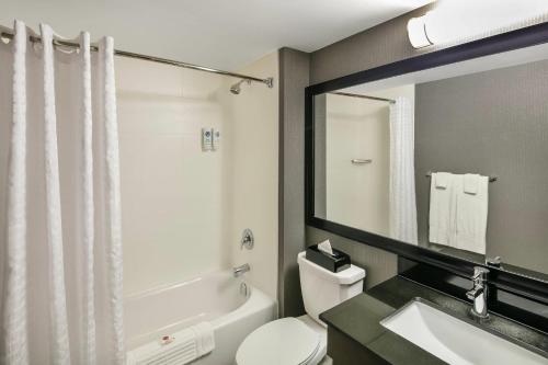 a bathroom with a toilet and a sink and a mirror at Comfort Inn Sydney - Cape Breton in Sydney