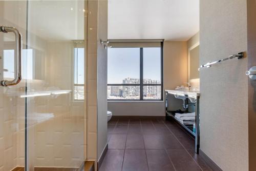 a bathroom with a shower and a toilet and a window at Cambria Hotel Washington DC Navy Yard Riverfront in Washington, D.C.