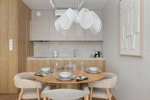 a kitchen with a wooden table with chairs and white cabinets at Essense Baltic Resort & SPA in Dziwnów