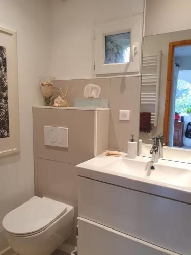 a white bathroom with a toilet and a sink at La Pastorale in Nyons