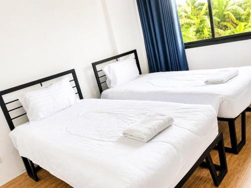 two beds in a room with white sheets at DM udon in Udon Thani
