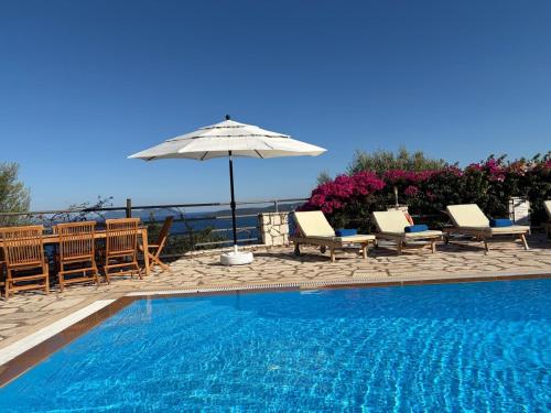 a swimming pool with chairs and an umbrella at Villa QuintaBella in Sivota