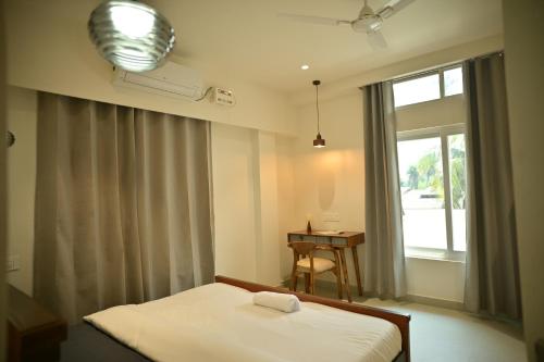a bedroom with a bed and a desk and a window at Noi Homes - Entire 2BHK Luxury Flat with Parking, Kitchen and Balcony in Jorhat