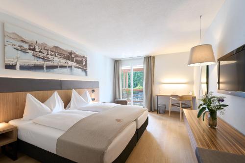 a hotel room with a large bed and a desk at Seehotel Kastanienbaum in Lucerne
