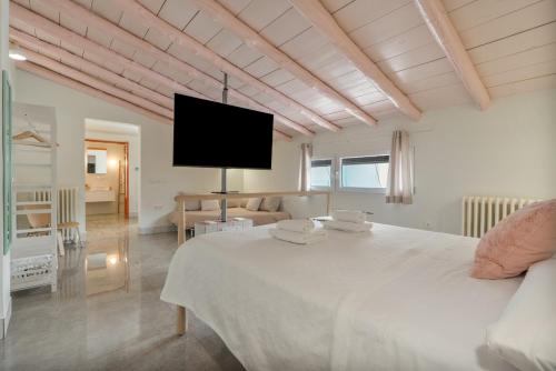 a white bedroom with a large bed and a tv at Raízes 22 - Apartamento 6 in Puebla de Don Fadrique