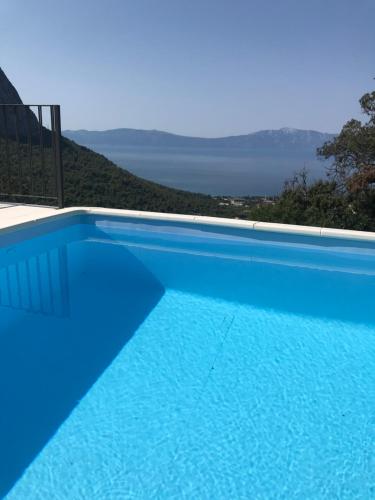 a blue swimming pool with a view of the ocean at HOLIDAY HOME m&n in Zaostrog
