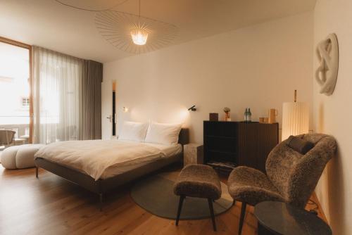 a hotel room with a bed and two chairs at Casa Caminada in Fürstenaubruck