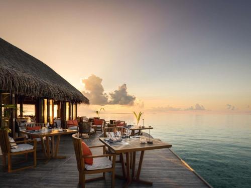 a restaurant on the water with tables and chairs at V Villas Maldives at Mirihi - MGallery Collection in Mandhoo