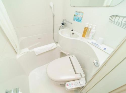 a white bathroom with a toilet and a sink at Super Hotel Kushiro Kurogane in Kushiro