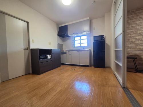 an empty kitchen with black appliances and a wooden floor at アパートメントホテル憩 in Yanagawa