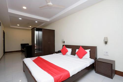 a bedroom with a large bed with red pillows at Hotel O Crown Hidden Residency in Satna