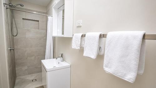 a bathroom with a sink and a shower and towels at Chambers Wildlife Rainforest Lodges in Lake Eacham