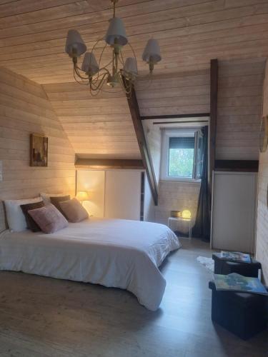 a bedroom with a large white bed with a wooden ceiling at La Crinière d'Or - Entre mer et campagne in Bonneville-la-Louvet