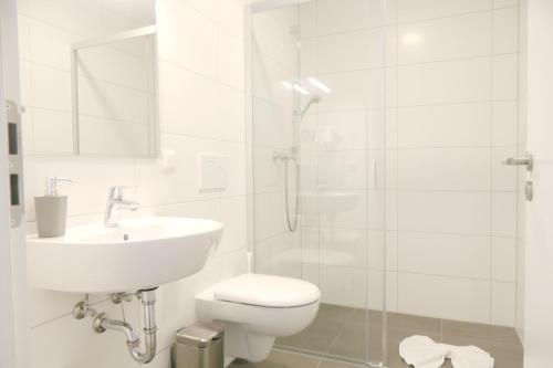 a white bathroom with a toilet and a sink at Gästehaus Gothensee in Heringsdorf