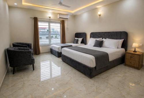 a bedroom with two beds and a chair and a window at Studio 13 in Islamabad