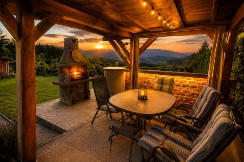 a patio with a table and chairs and a fireplace at Hiška Miru Peace Cabin in Mozirje