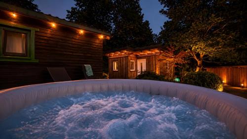 a hot tub in front of a house at night at Hiška Miru Peace Cabin in Mozirje