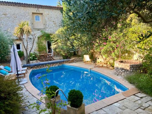a swimming pool in front of a house at La Maison Des Autres, piscine chauffée, chambres d'hôtes, proche d'Uzès, Nîmes, Pont du Gard, Alès in Saint-Géniès-de-Malgoirès