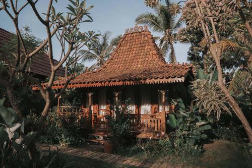 a house with a thatched roof in a garden at Kusfarm Bali by AHM in Selemadeg