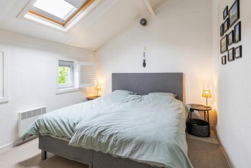 a bedroom with a large bed and two windows at Sea Side Village 91 in De Haan