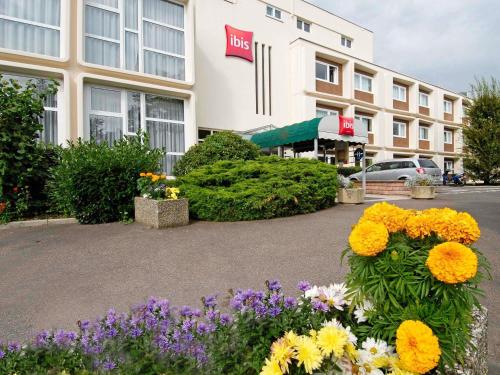 a hotel with flowers in front of a building at ibis Belfort Danjoutin in Belfort