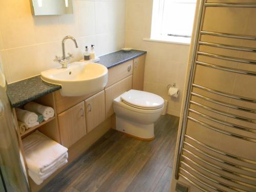a bathroom with a white toilet and a sink at Stratton Gardens in Bude