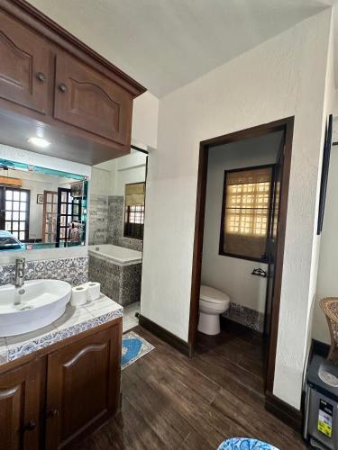 a bathroom with a sink and a toilet and a tub at Casa Del Faro in Puerto Galera
