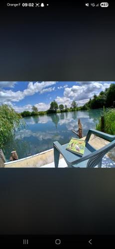 a picture of a lake with a table and a book at Chez Bernard in Mareuil-Caubert