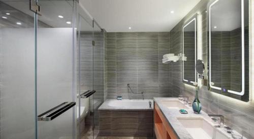 a bathroom with a tub and a sink and a shower at Shama Daqing Heilongjiang in Daqing