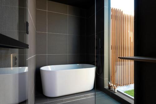 a bathroom with a white tub and a window at BLUE BLACK blue black in Karatsu