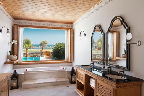a bathroom with a tub and a sink and a window at Mitsis Selection Blue Domes in Kardamaina