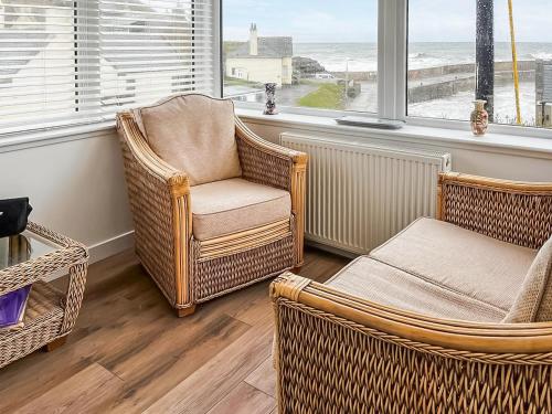 a living room with wicker chairs and a table at The Anchorage in Collieston