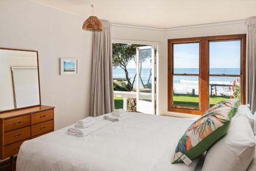 a bedroom with a bed and a large window at Beachfront Kiwi bach with direct beach access in Gisborne