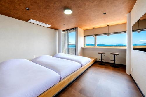 two beds in a room with a view of the ocean at VillaMer KAWACHI in Kumamoto