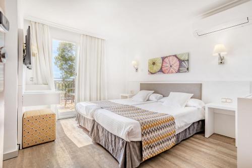 a hotel room with a bed and a window at Morlans Garden in Paguera