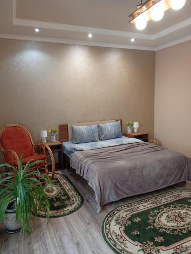 a bedroom with a bed and a chair and two rugs at Gray in Ternopil