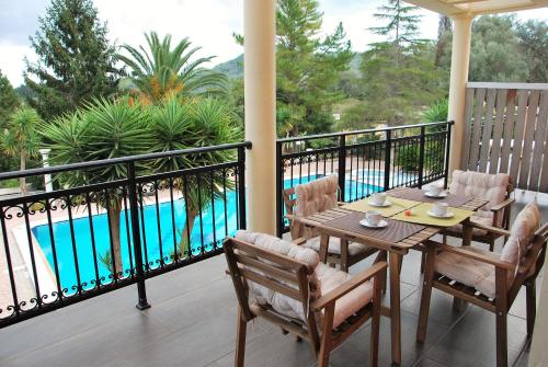 un tavolo e sedie su un balcone con piscina di Corfu Pearl a Liapades