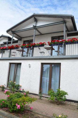 a white house with flowers on the balconies at Hotel-Pension Pastow Garni in Broderstorf
