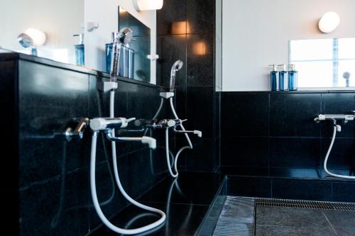 a shower in a bathroom with a black wall at VillaMer KAWACHI in Kumamoto