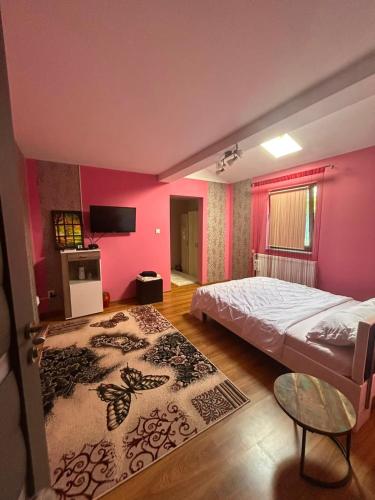 a bedroom with a large bed and pink walls at Colț de rai - camera de inchiriat in Reşiţa