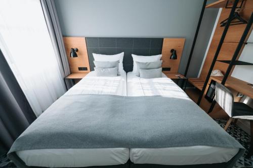 a bedroom with a large bed with two pillows at Feringapark Hotel by Coffee Fellows Hotels in Munich