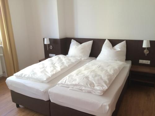 two beds in a room with white sheets and pillows at Alte Post in Bad Griesbach