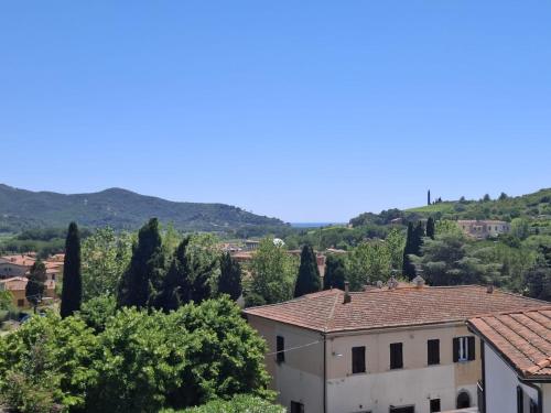 a building with trees and mountains in the background at Appartamento Losanna in Campo nell'Elba