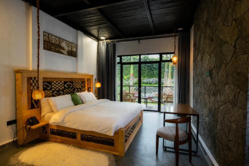a bedroom with a bed and a desk and a window at Grotta Resort in Gasanze