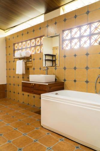a bathroom with a tub and a sink and a mirror at La Vela Legacy Resort in Thôn Dương Xuân Hạ