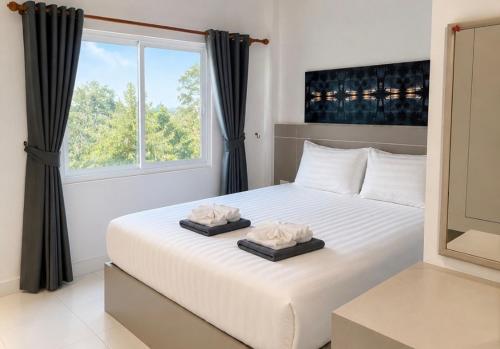 a bedroom with a large white bed with a window at SET INN restaurant & bar 1 & 2 in Kata Beach
