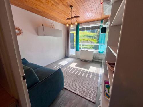 a living room with a blue couch and a window at Studio cosy avec balcon et vue sur la montagne à Chamrousse - 19 m² in Chamrousse