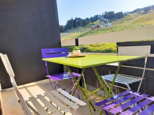 a table with purple chairs and a green table and chairs at Studio cosy avec balcon et vue sur la montagne à Chamrousse - 19 m² in Chamrousse
